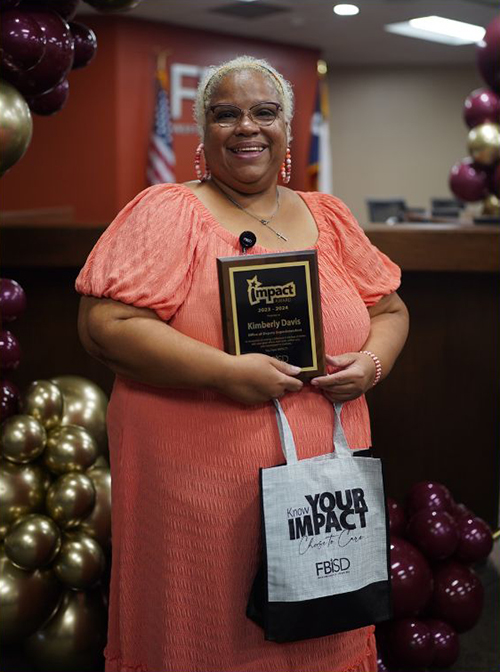Kim Davis holding the Impact Award plaque